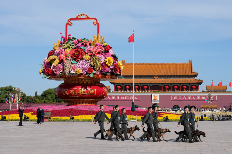Security officials walk with dogs in Tiananmen Square.